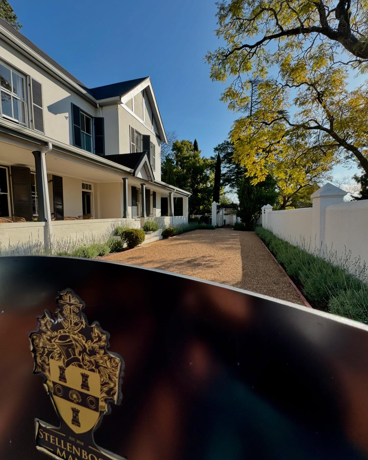 Two-storey white manor with dark shutters and a long porch