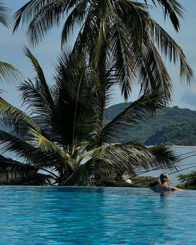 A woman in a blue swimsuit relaxes in an infinity pool